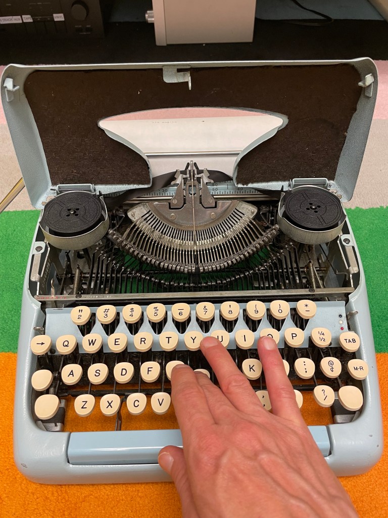 hand pressing typewriter keys of light blue Tower mechanical typewriter